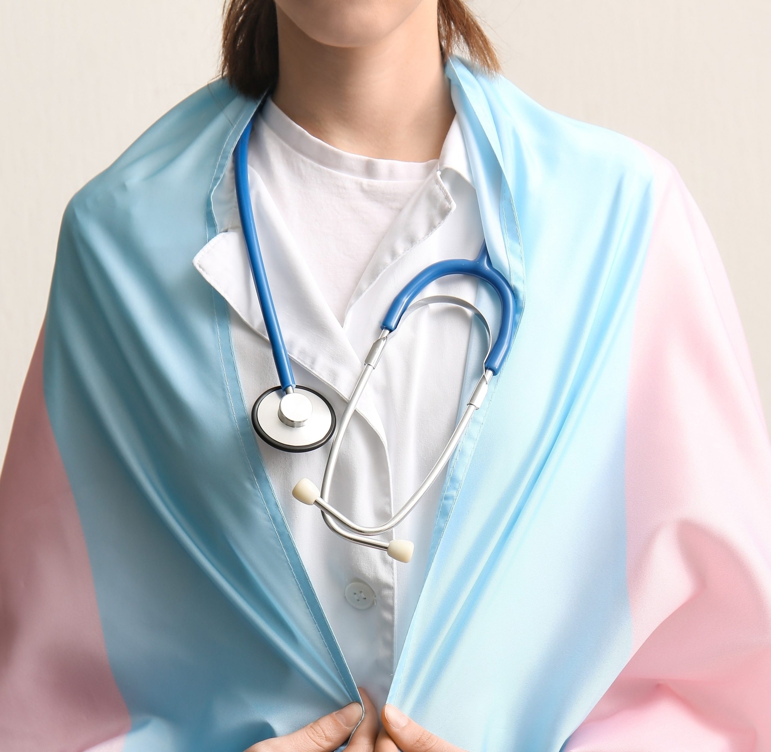 Doctor with transgender flag on light background with space for text
